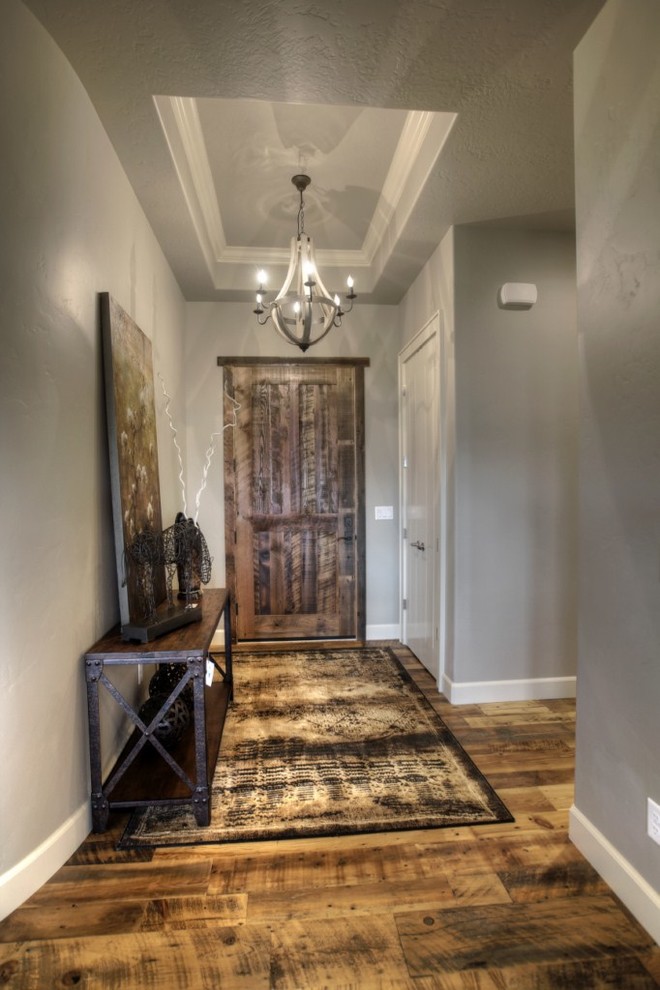 Immagine di un ingresso tradizionale di medie dimensioni con pareti grigie, pavimento in legno massello medio, una porta singola, una porta in legno scuro e pavimento marrone