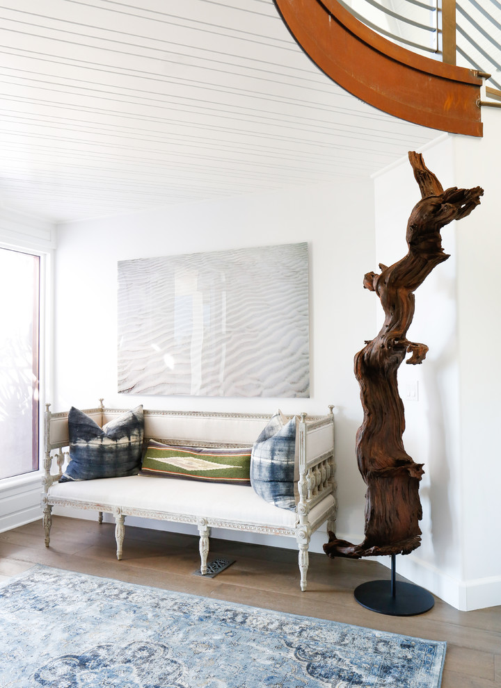 Inspiration for a coastal entrance in Orange County with white walls and light hardwood flooring.