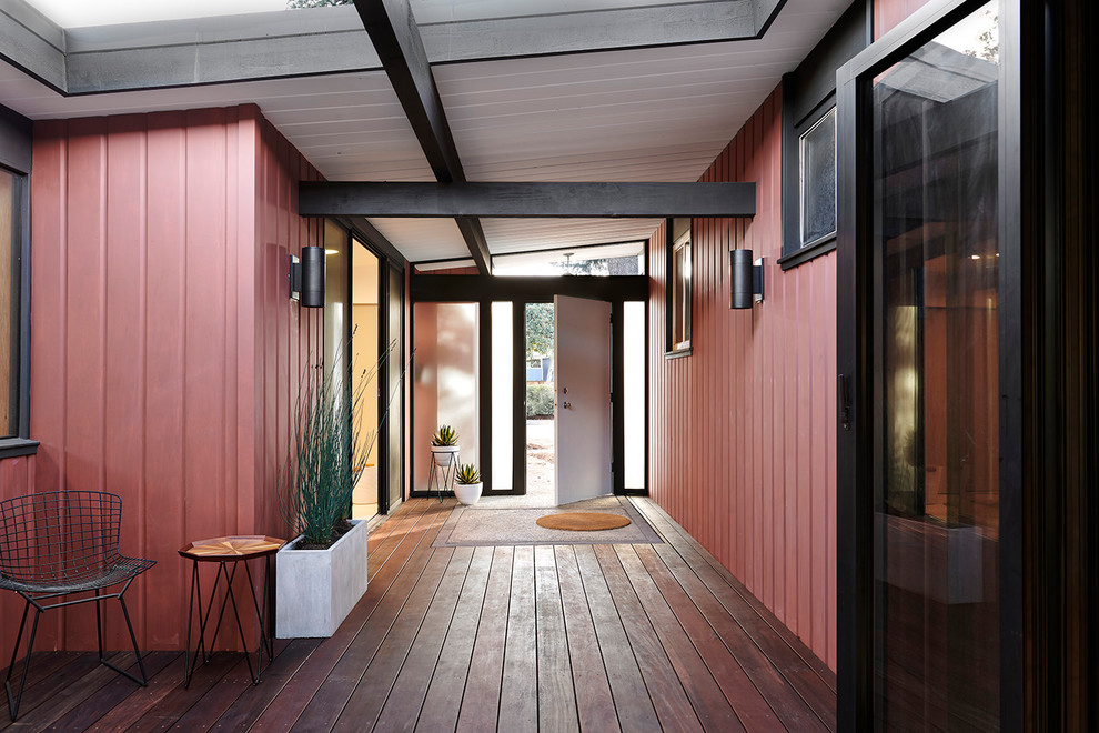 Aménagement d'une entrée rétro avec un mur rouge, parquet foncé, un couloir, une porte simple, une porte blanche et un sol marron.
