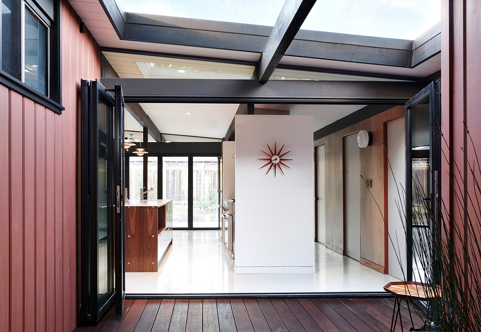 Aménagement d'un petit hall d'entrée rétro avec un mur rouge, un sol en vinyl, une porte en verre et un sol blanc.