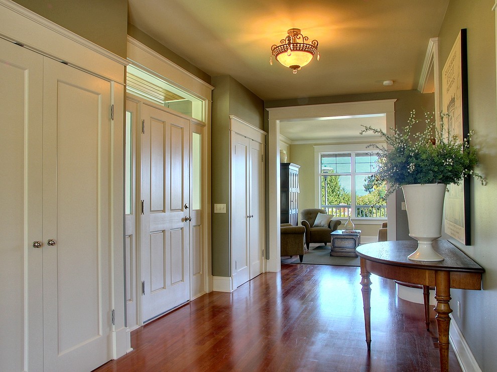Diseño de hall clásico con paredes verdes y suelo de madera en tonos medios
