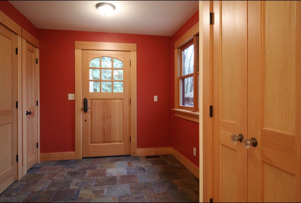 Bild på en amerikansk foajé, med röda väggar, skiffergolv, en enkeldörr och ljus trädörr