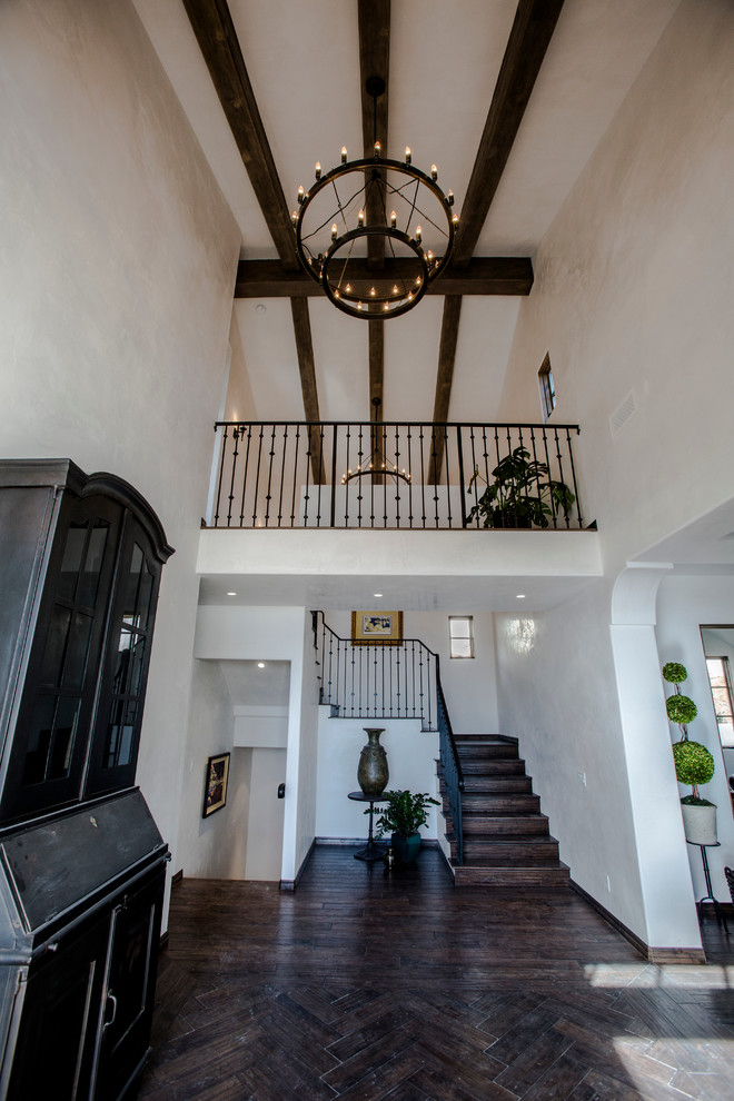 Example of a large tuscan dark wood floor and brown floor entryway design in Santa Barbara with beige walls and a black front door