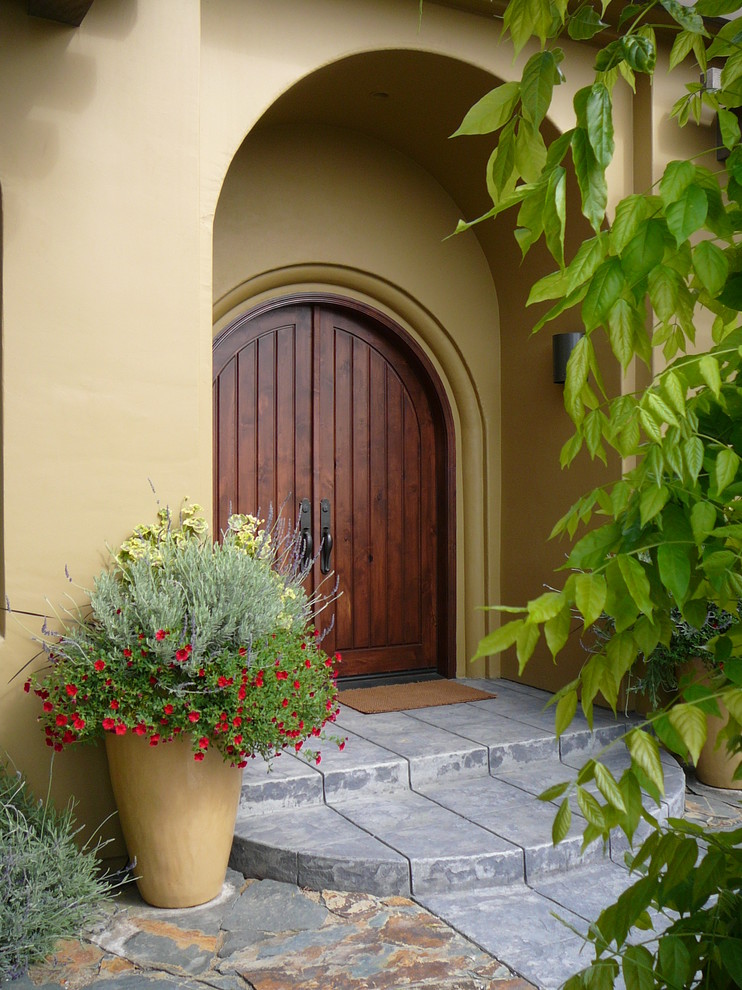 Стильный дизайн: входная дверь в средиземноморском стиле с желтыми стенами, двустворчатой входной дверью и входной дверью из дерева среднего тона - последний тренд