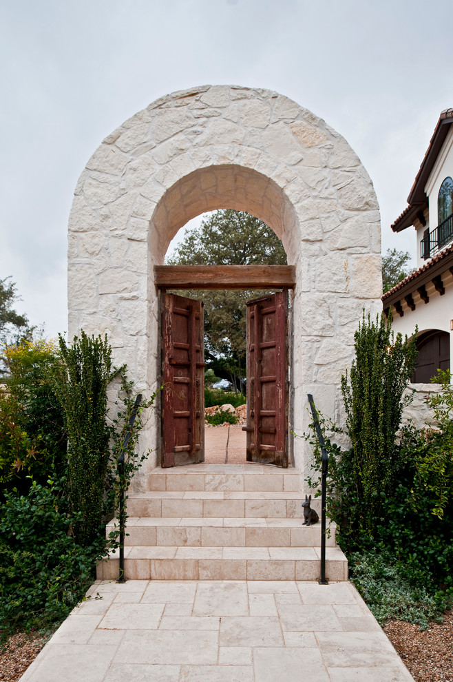 Expansive mediterranean foyer in Austin with white walls, limestone flooring, a double front door and a dark wood front door.