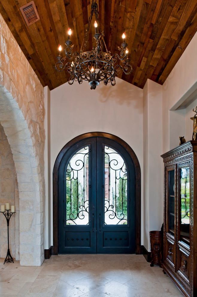 Стильный дизайн: огромная входная дверь в средиземноморском стиле с бежевыми стенами, полом из травертина, двустворчатой входной дверью и черной входной дверью - последний тренд