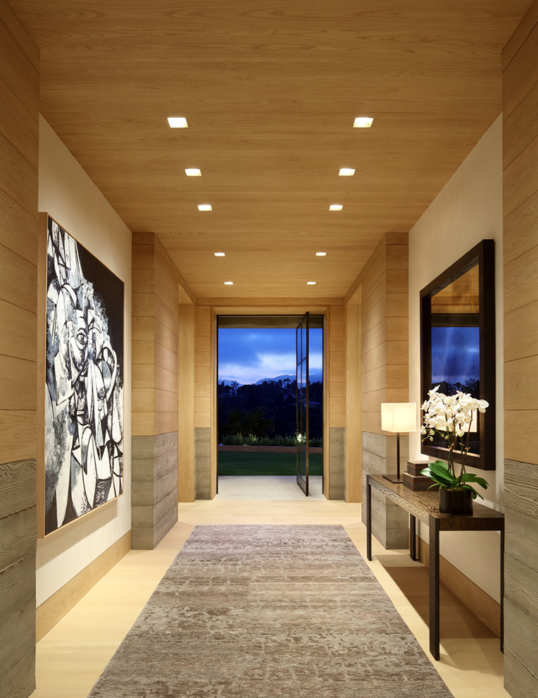 На фото: узкая прихожая: освещение в современном стиле с разноцветными стенами, светлым паркетным полом, поворотной входной дверью и стеклянной входной дверью с