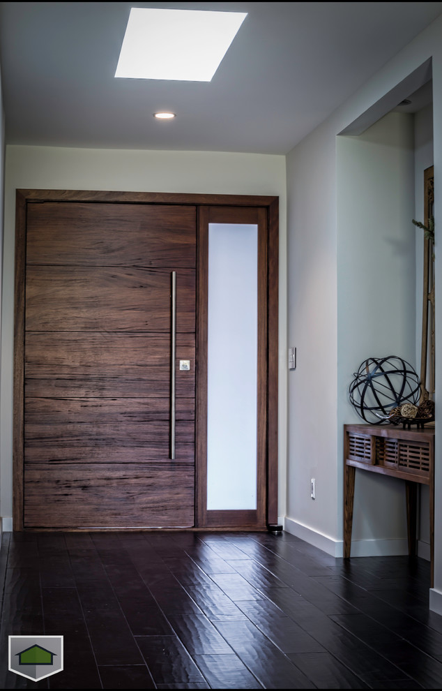Foto de distribuidor actual de tamaño medio con paredes grises, puerta simple y puerta de madera oscura