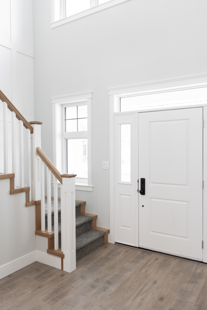 Idee per un ingresso country di medie dimensioni con pareti bianche, pavimento in legno massello medio, una porta singola, una porta bianca e pavimento marrone