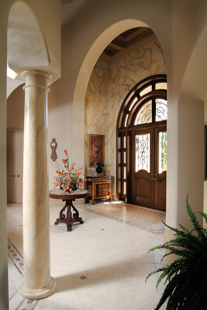 Cette image montre un grand hall d'entrée méditerranéen avec un mur beige, un sol en carrelage de céramique, une porte double et une porte en bois foncé.
