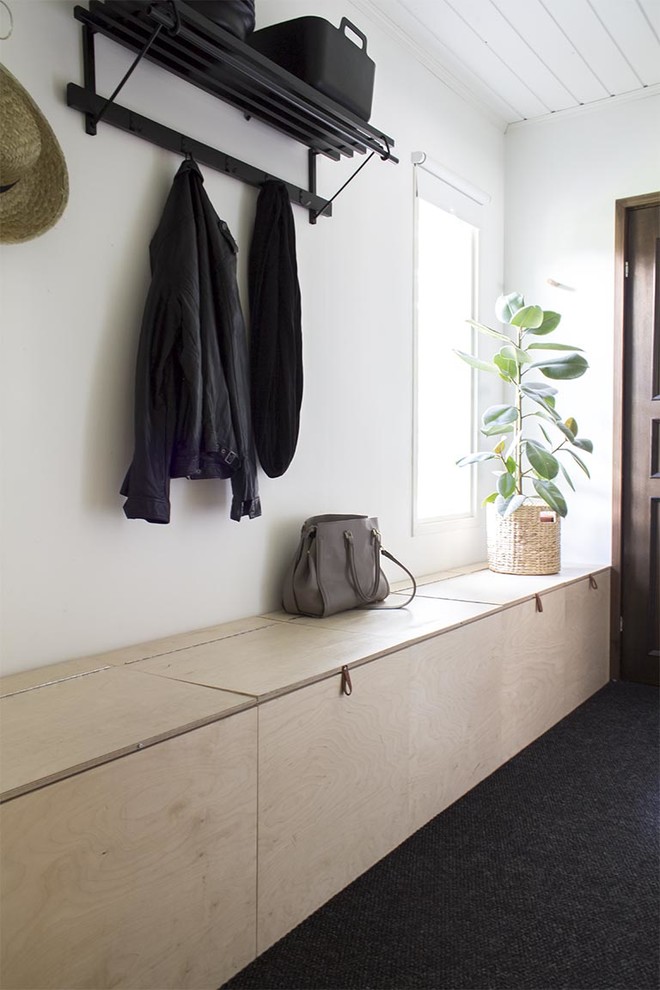 This is an example of a scandinavian boot room in London with white walls and carpet.