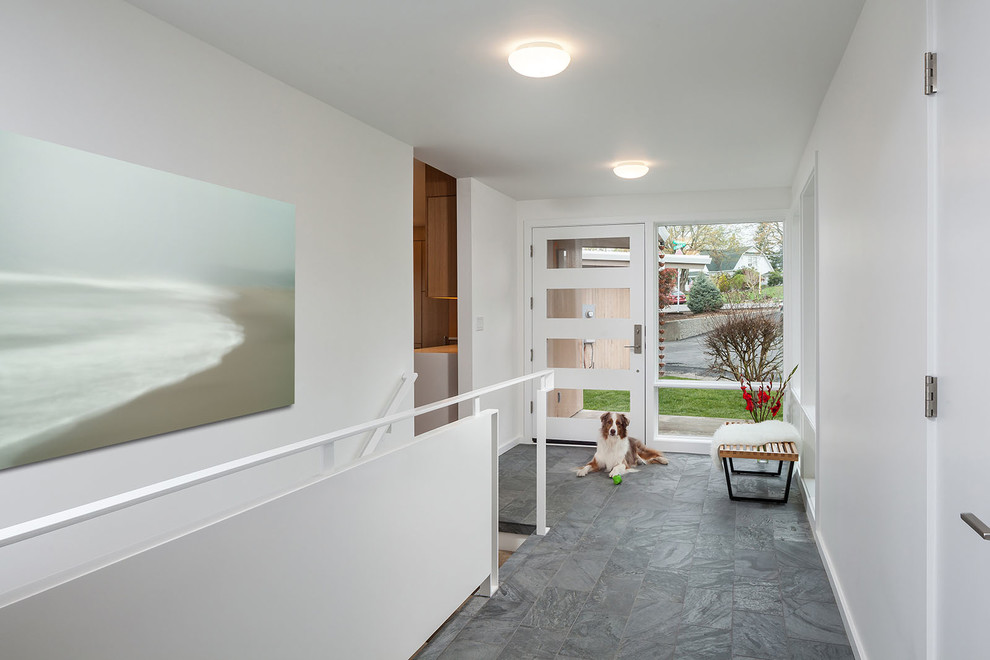 Photo of a contemporary hallway in Portland with white walls, a single front door, a glass front door and grey floors.