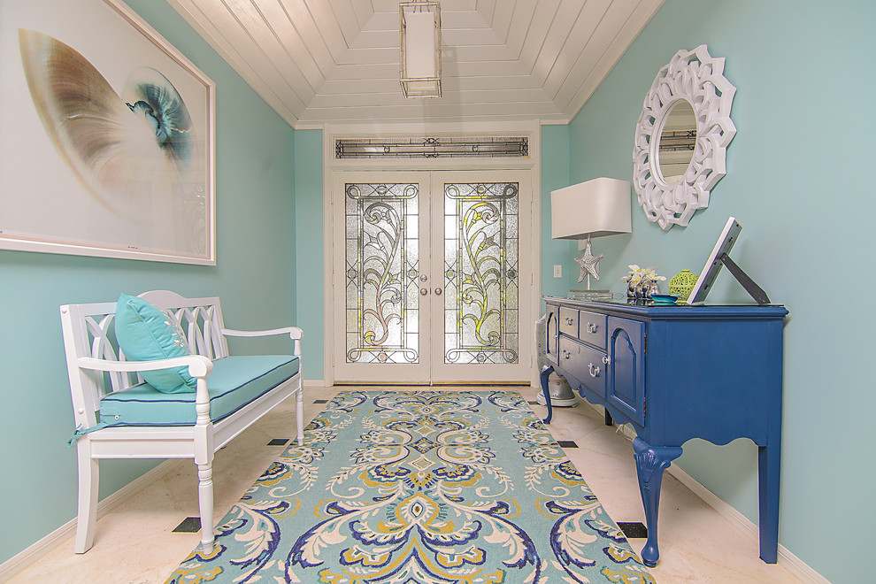 マイアミにある高級な小さなビーチスタイルのおしゃれな玄関ドア (青い壁、トラバーチンの床、白いドア) の写真