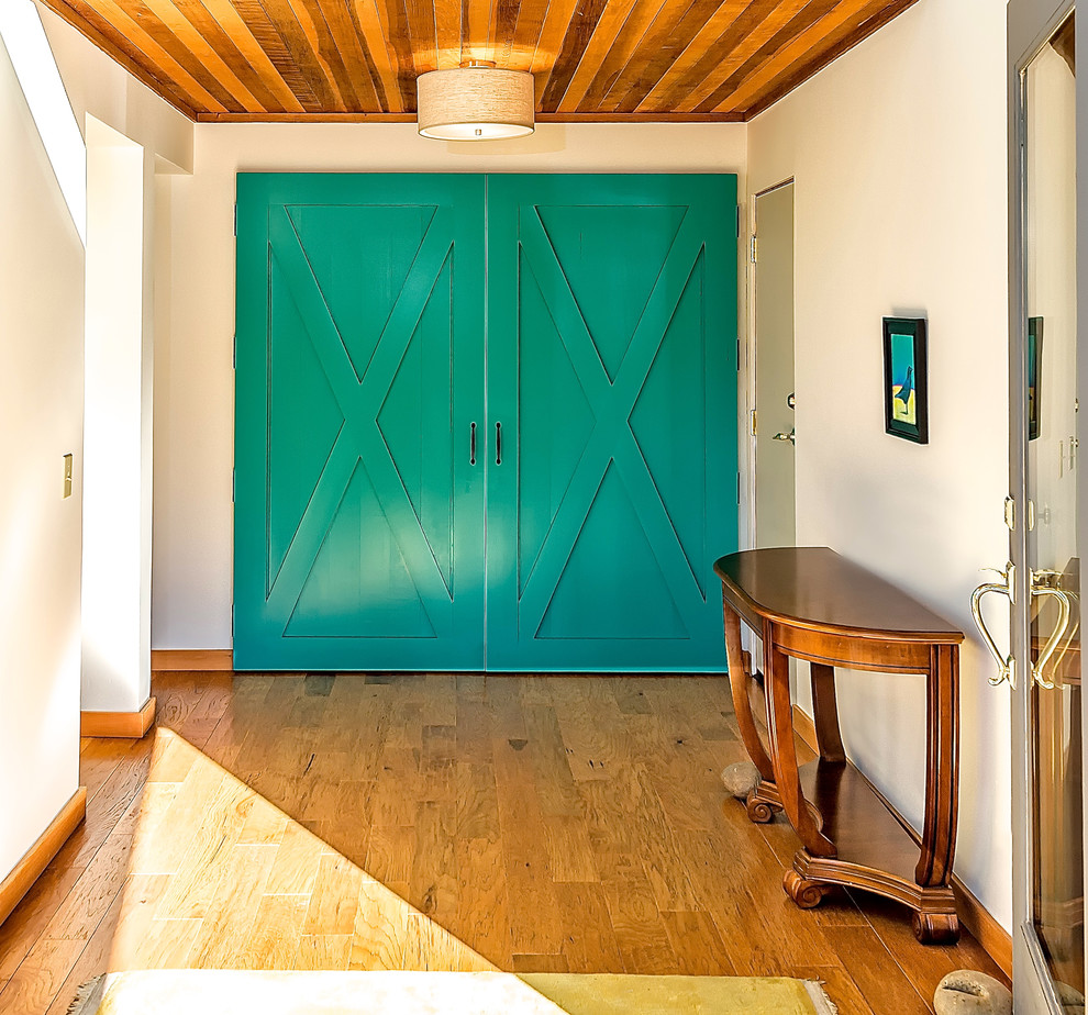 Immagine di un ingresso stile rurale di medie dimensioni con pareti bianche, pavimento in legno massello medio, una porta a pivot e una porta in vetro