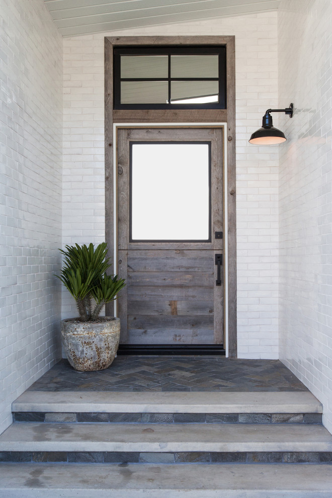 Imagen de puerta principal marinera de tamaño medio con paredes blancas, suelo de pizarra, puerta simple, puerta de madera en tonos medios y suelo azul