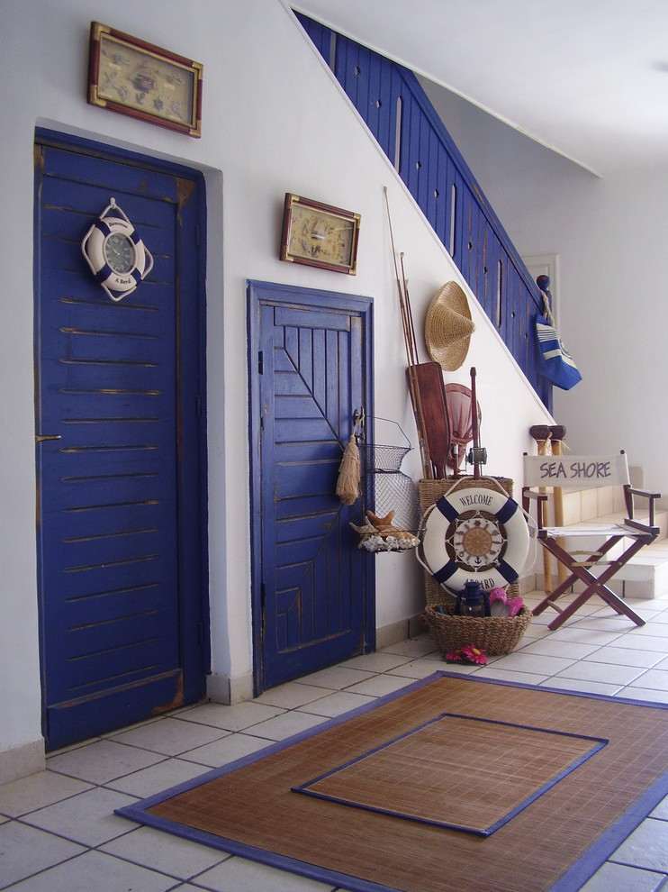 На фото: фойе среднего размера в морском стиле с белыми стенами, полом из керамической плитки, одностворчатой входной дверью и серым полом