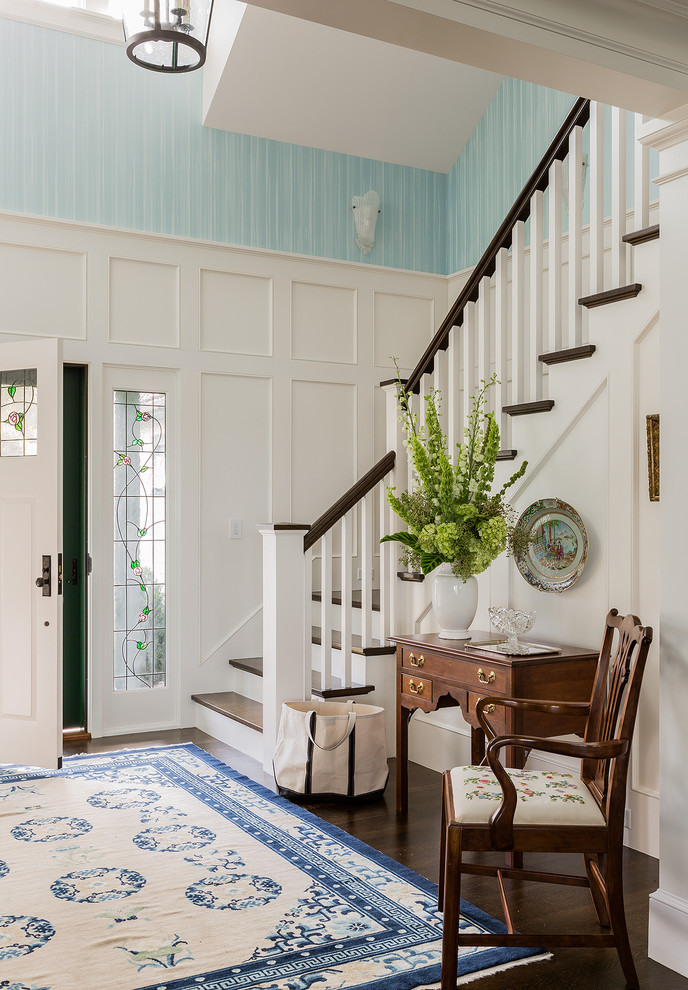 Klassisches Foyer mit blauer Wandfarbe, dunklem Holzboden, Einzeltür und weißer Haustür in Boston
