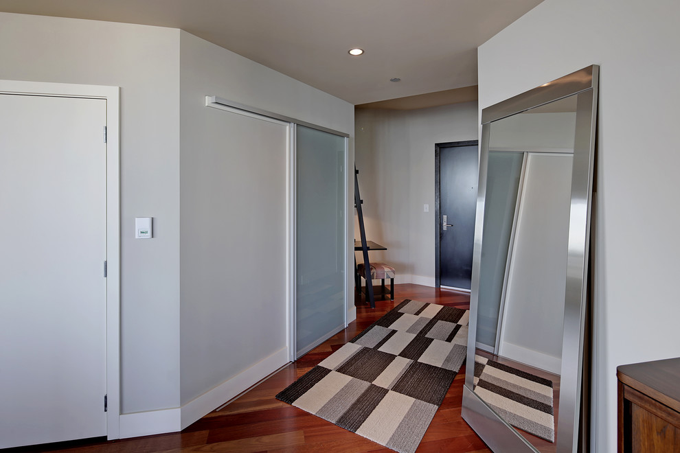 Inspiration pour un petit hall d'entrée design avec un mur gris, un sol en bois brun, une porte simple et une porte en bois foncé.