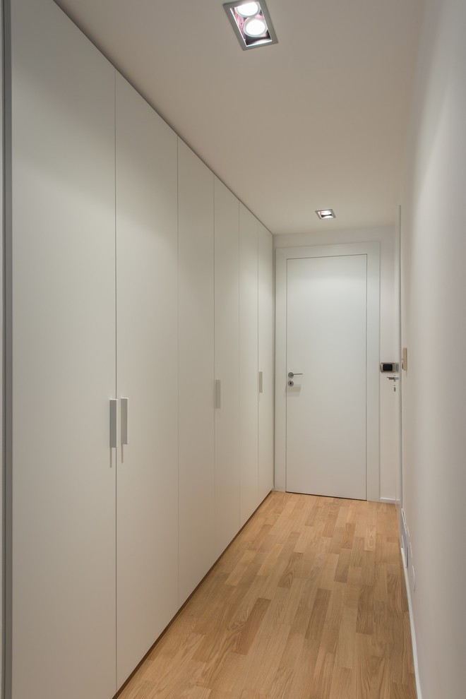 Idées déco pour une entrée moderne de taille moyenne avec un couloir, un mur blanc, un sol en bois brun, une porte simple, une porte blanche et un sol marron.