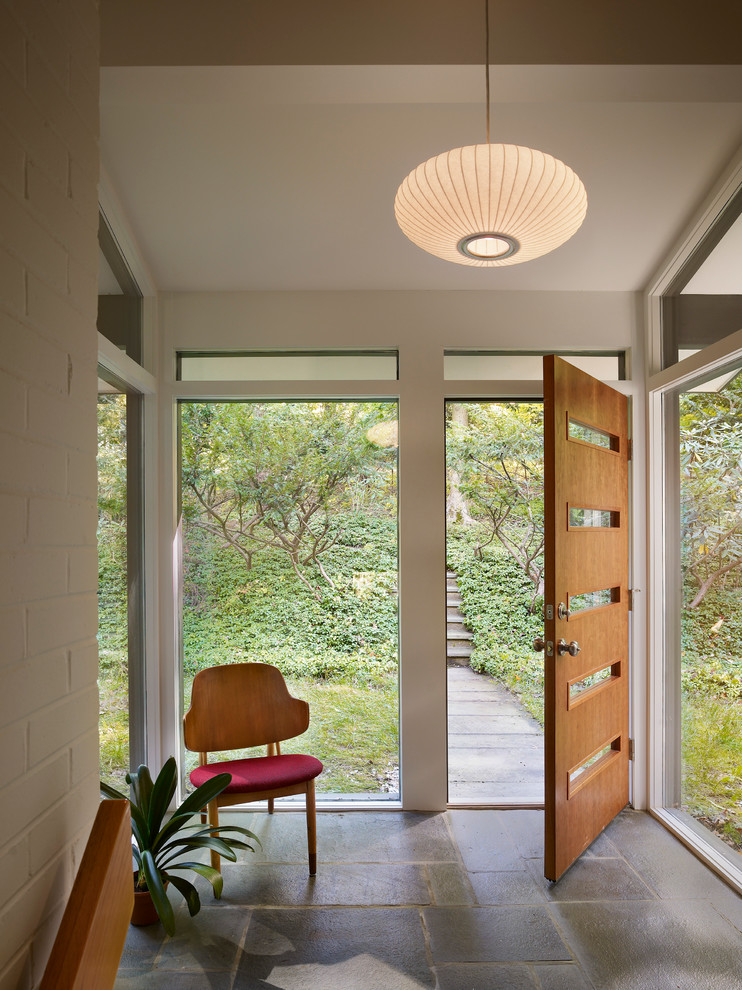Esempio di un ingresso o corridoio minimalista con una porta singola, una porta in legno bruno e pavimento grigio