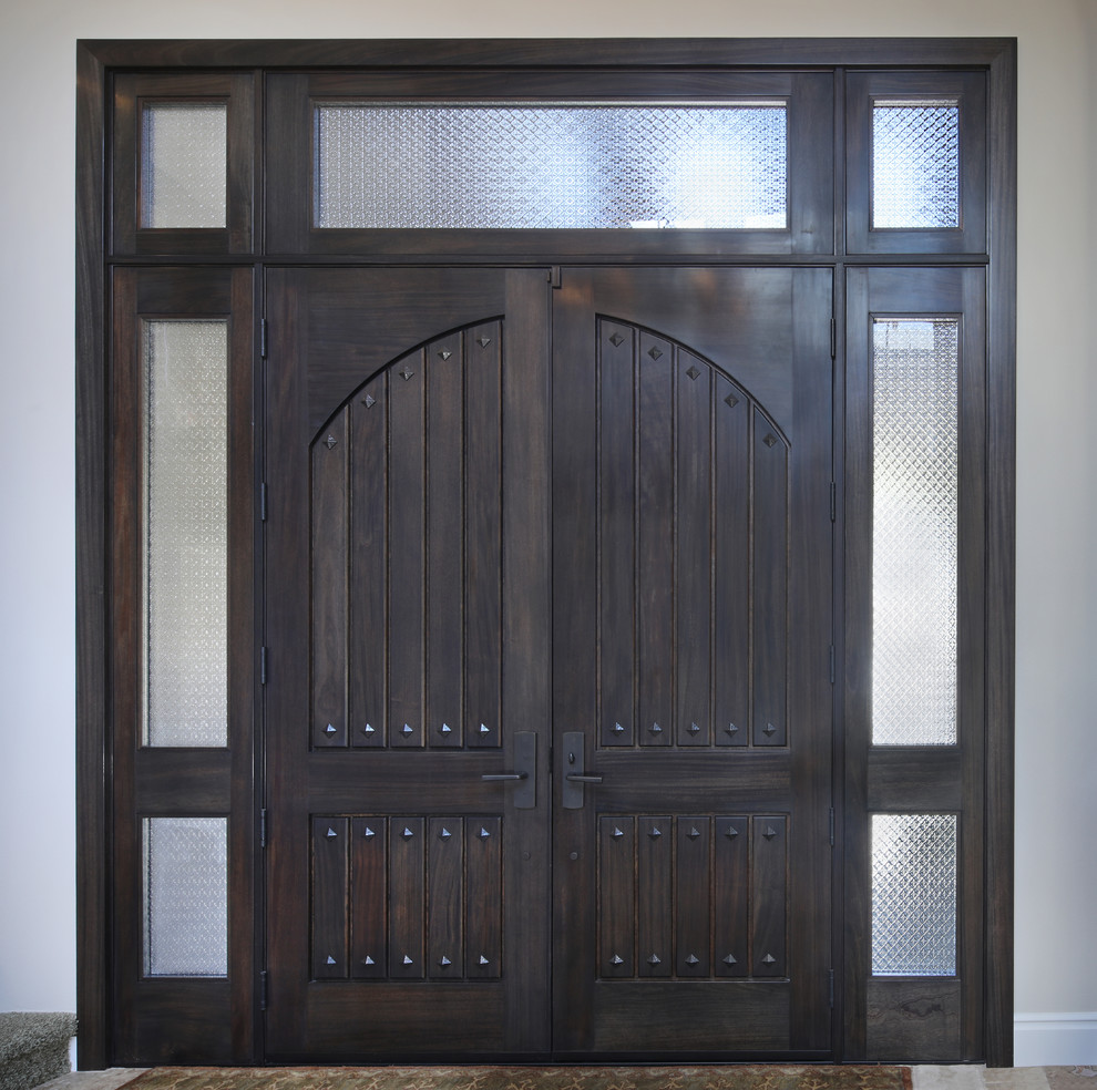 На фото: огромная входная дверь в классическом стиле с бежевыми стенами, полом из травертина, двустворчатой входной дверью, входной дверью из темного дерева и коричневым полом с