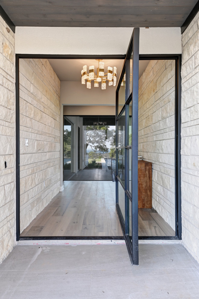 Example of a trendy light wood floor entryway design in Austin with white walls and a black front door