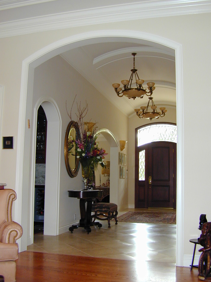 Diseño de hall tradicional grande con paredes beige, suelo de baldosas de porcelana, puerta simple y puerta de madera oscura