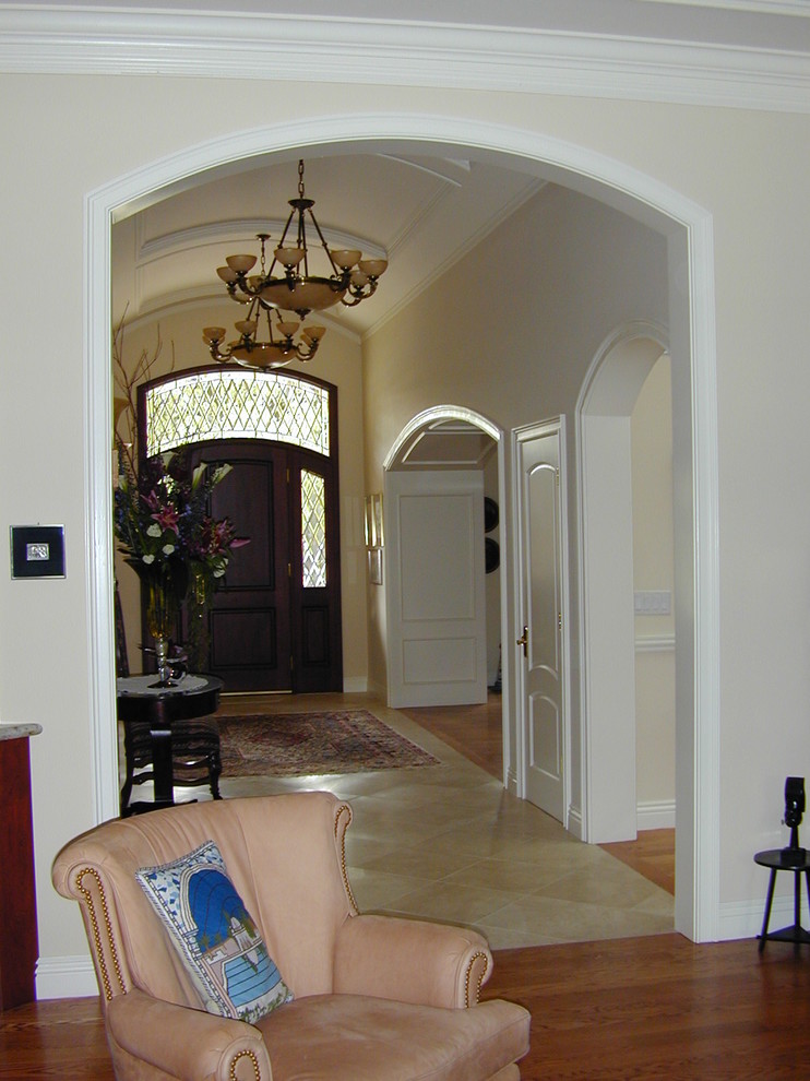 Foto di un grande corridoio chic con pareti beige, pavimento in gres porcellanato, una porta singola e una porta in legno scuro