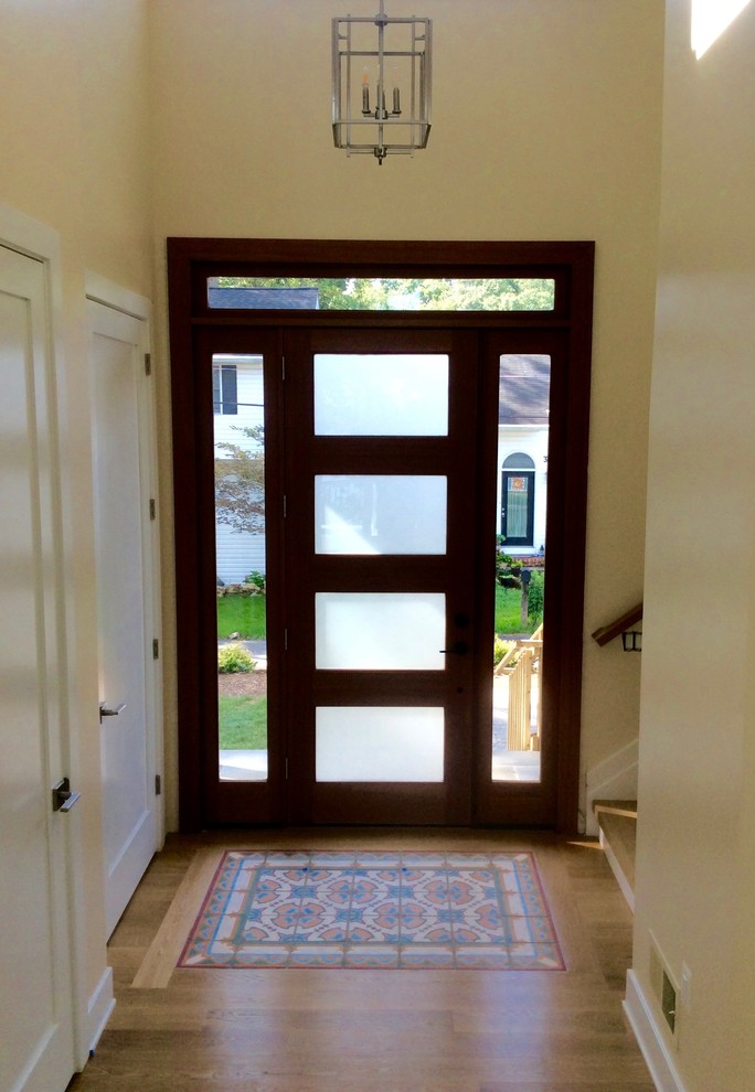 Immagine di un corridoio design di medie dimensioni con pareti bianche, parquet chiaro e una porta in vetro