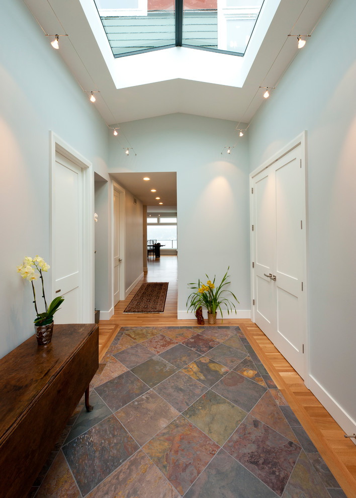 Cette image montre un hall d'entrée design de taille moyenne avec un sol en ardoise, une porte simple et un mur gris.