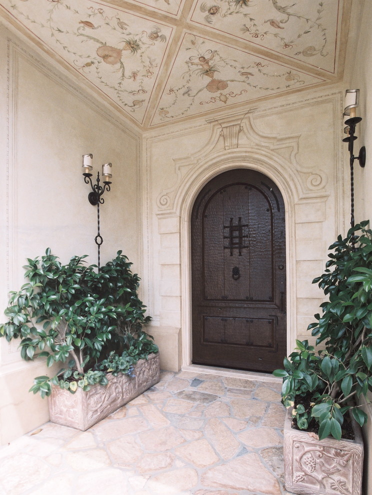 Esempio di un ampio ingresso o corridoio mediterraneo con pareti multicolore, pavimento in pietra calcarea, una porta singola, una porta in legno scuro, pavimento multicolore e soffitto ribassato