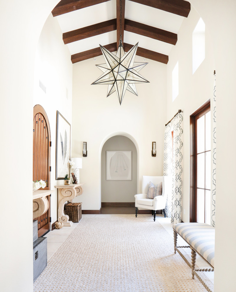 Photo of a large mediterranean foyer in Orange County with white walls, a single front door and a dark wood front door.