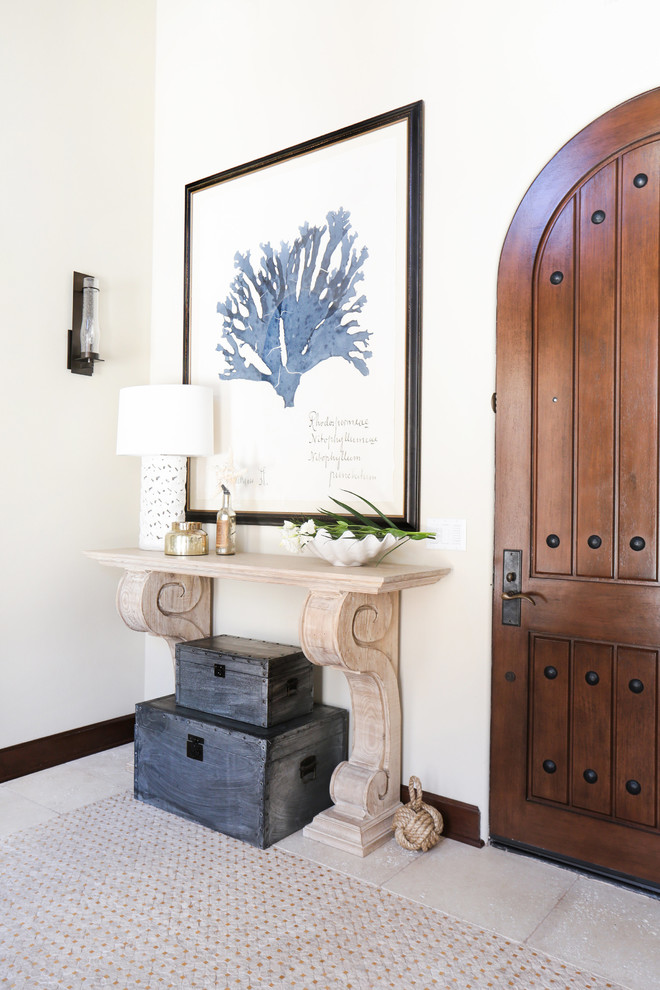 This is an example of a large traditional foyer in Orange County with white walls, a single front door, a dark wood front door and feature lighting.