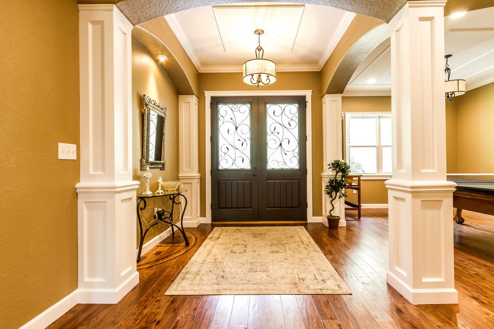Foto di un ingresso american style di medie dimensioni con pareti beige, pavimento in legno massello medio, una porta a due ante e una porta in legno scuro