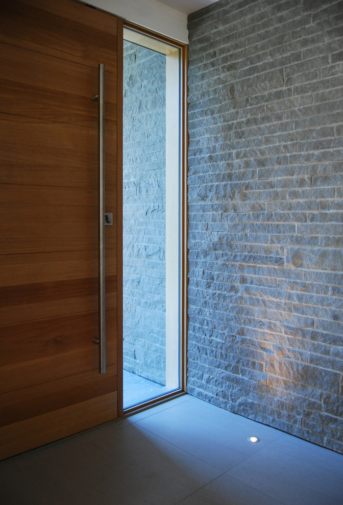 Cette photo montre une grande porte d'entrée moderne avec un mur gris, un sol en carrelage de porcelaine, une porte simple et une porte en bois brun.