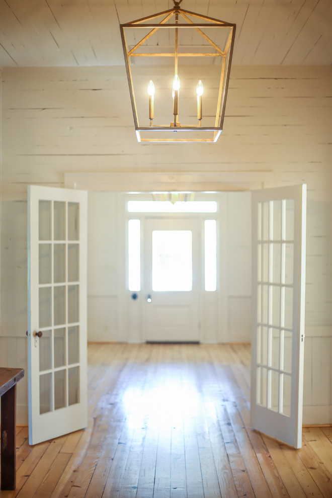 На фото: большое фойе в стиле кантри с белыми стенами, светлым паркетным полом, одностворчатой входной дверью, белой входной дверью и коричневым полом с