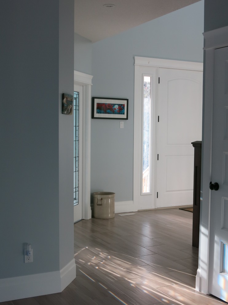 Großes Country Foyer mit grauer Wandfarbe, Porzellan-Bodenfliesen, Einzeltür und weißer Haustür in Edmonton