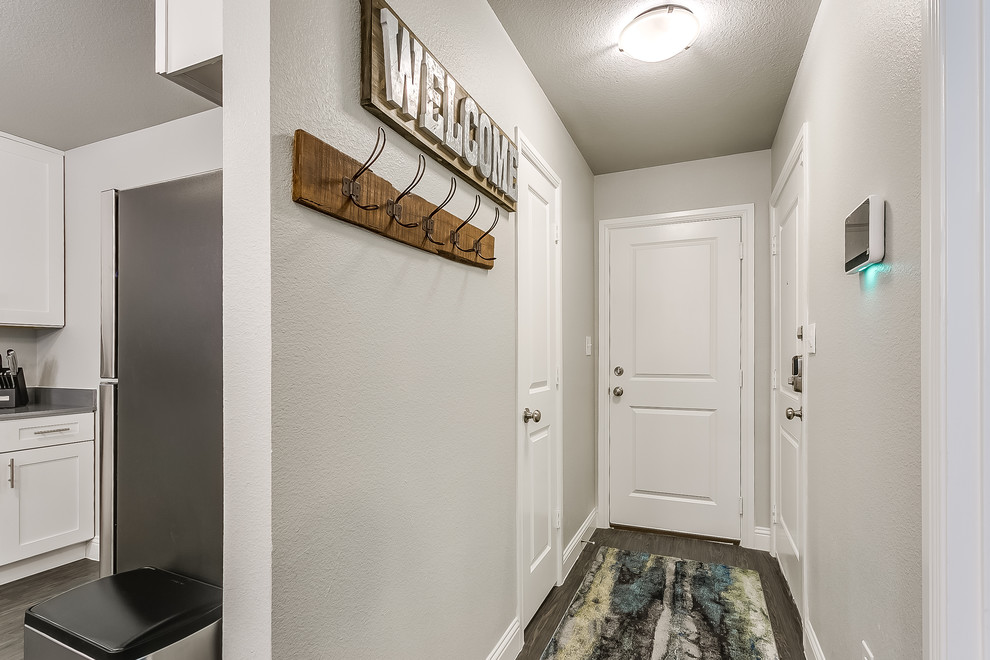 ダラスにある小さなトランジショナルスタイルのおしゃれな玄関ドア (グレーの壁、ラミネートの床、白いドア、グレーの床) の写真