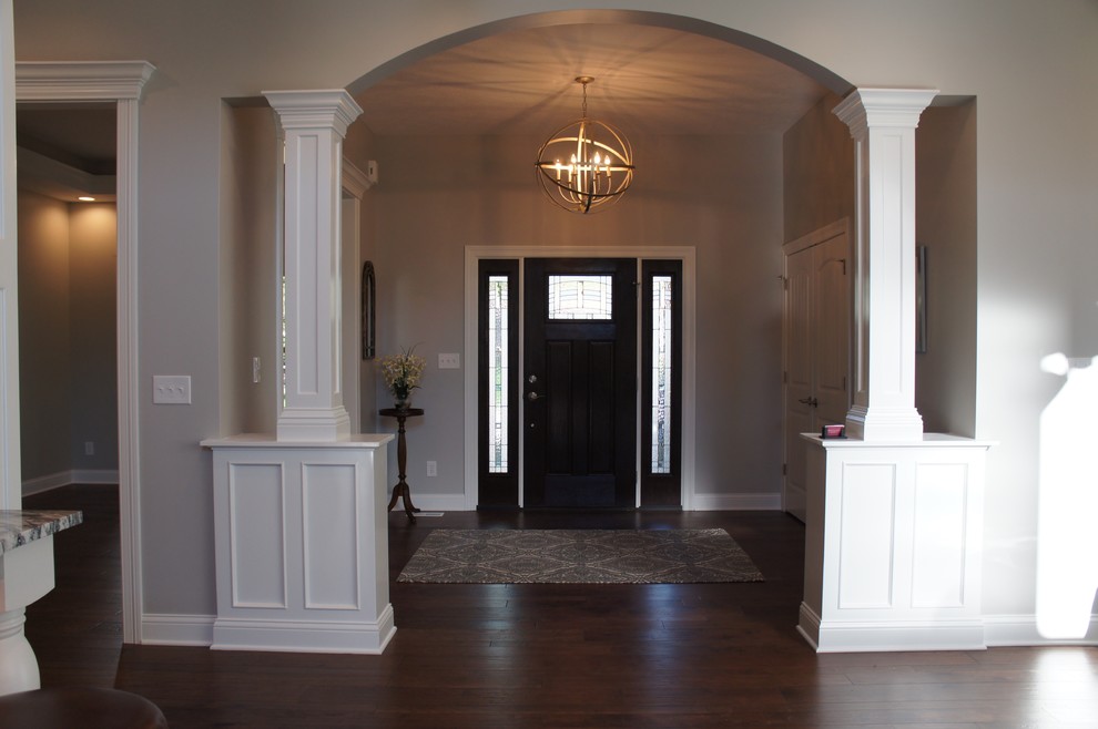 Cette image montre un hall d'entrée traditionnel avec un mur beige, parquet foncé, une porte simple et une porte en bois foncé.