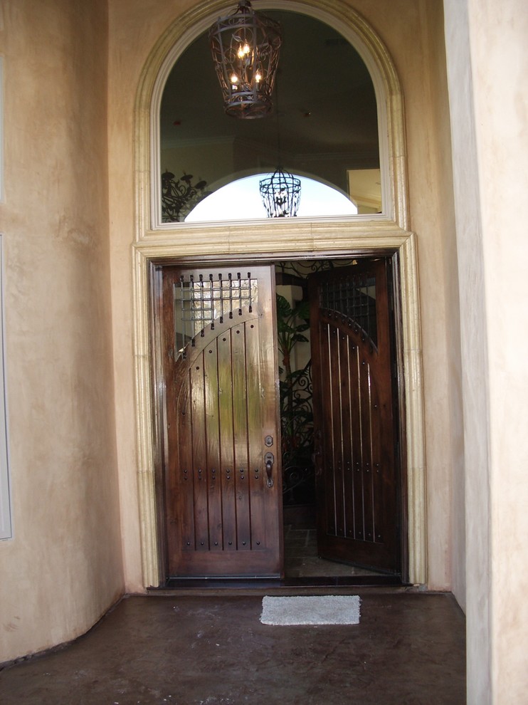 Стильный дизайн: входная дверь среднего размера в средиземноморском стиле с бежевыми стенами, бетонным полом, двустворчатой входной дверью, входной дверью из темного дерева и красным полом - последний тренд
