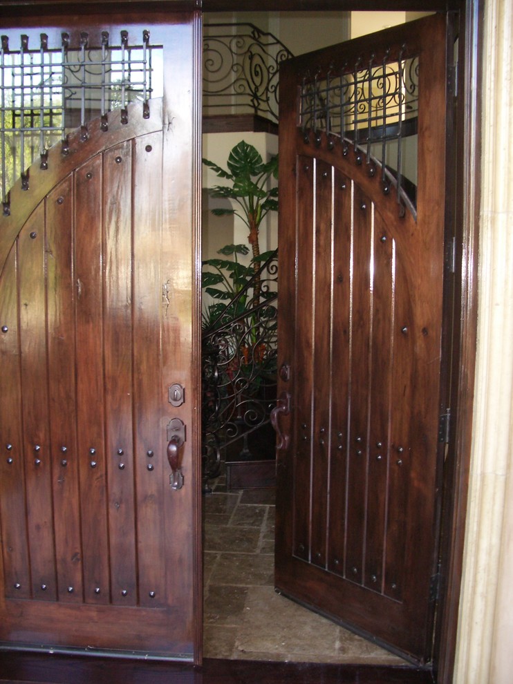 Foto di una porta d'ingresso mediterranea di medie dimensioni con pareti beige, pavimento in travertino, una porta a due ante, una porta in legno scuro e pavimento rosso