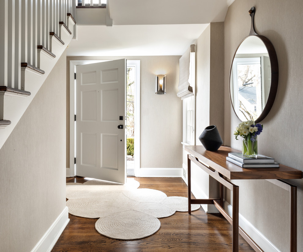 Idée de décoration pour une entrée tradition avec un couloir, un mur gris, un sol en bois brun, une porte simple, une porte blanche et un sol marron.