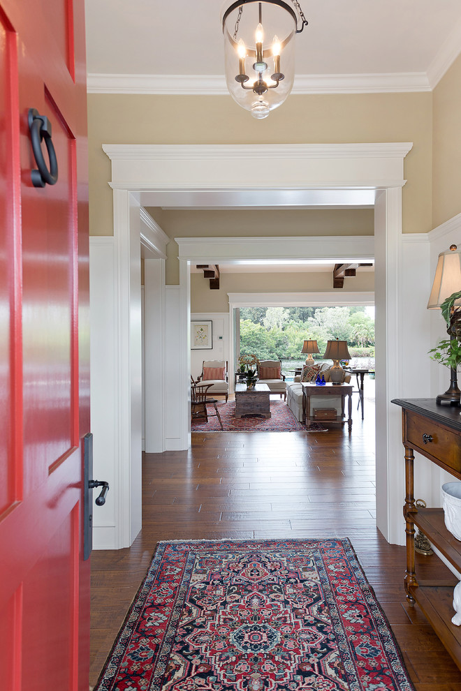 Esempio di un ingresso classico di medie dimensioni con pareti beige, parquet scuro, una porta singola, una porta rossa e pavimento marrone