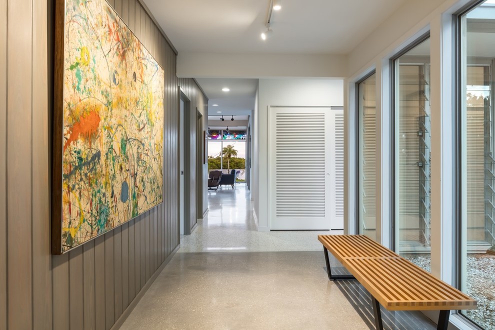 Immagine di un corridoio moderno di medie dimensioni con pareti beige, pavimento in cemento, una porta singola, una porta verde e pavimento grigio