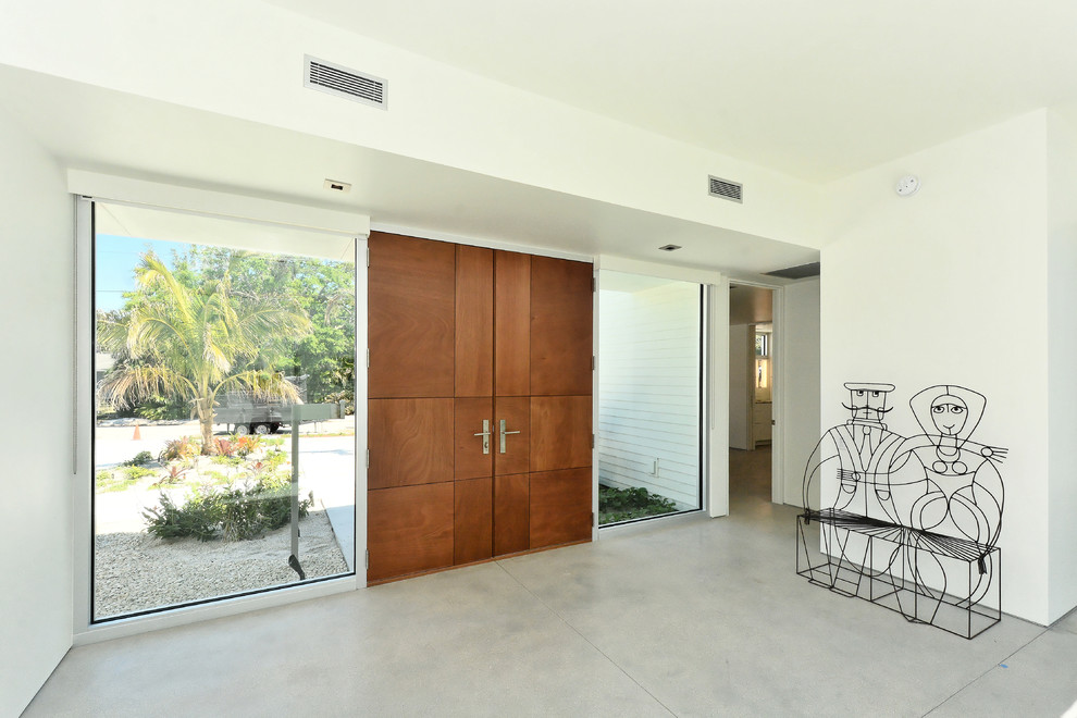На фото: входная дверь среднего размера в стиле модернизм с белыми стенами, бетонным полом, двустворчатой входной дверью, входной дверью из дерева среднего тона и серым полом