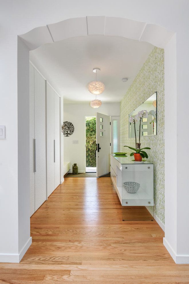 This is an example of a medium sized contemporary front door in Los Angeles with white walls, medium hardwood flooring, a single front door, a white front door and brown floors.