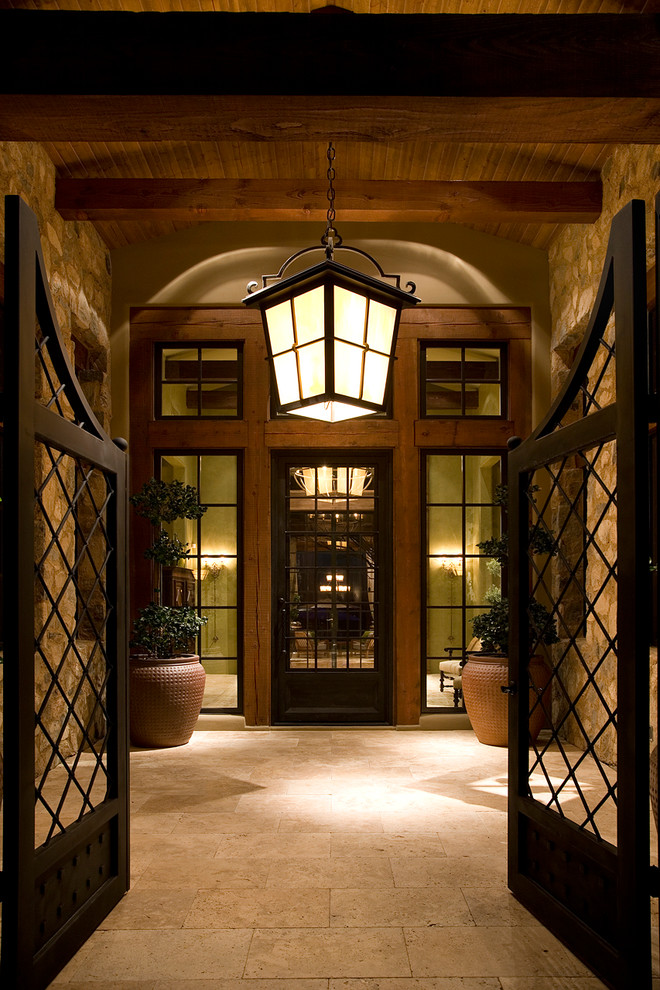 This is an example of a mediterranean vestibule in Phoenix with a glass front door and feature lighting.