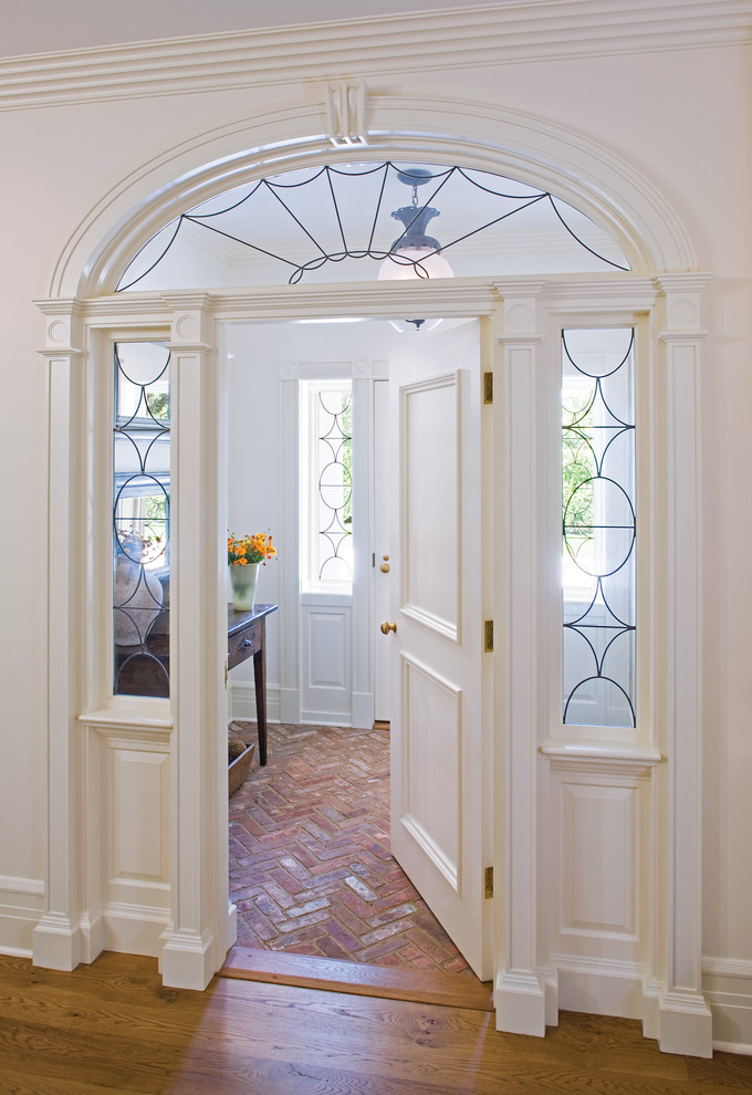 Foto de entrada tradicional con paredes blancas, suelo de ladrillo, puerta simple y puerta blanca