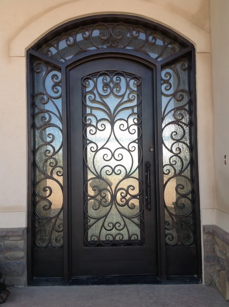 На фото: большая входная дверь в средиземноморском стиле с бежевыми стенами и одностворчатой входной дверью