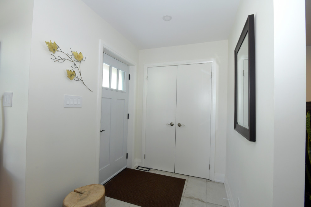 Esempio di una piccola porta d'ingresso tradizionale con pareti bianche, pavimento in gres porcellanato, una porta singola e una porta bianca